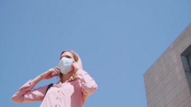 Güzel sarışın bir kadının maskesini çıkardığı ve sokakta temiz havanın tadını çıkardığı bir video..