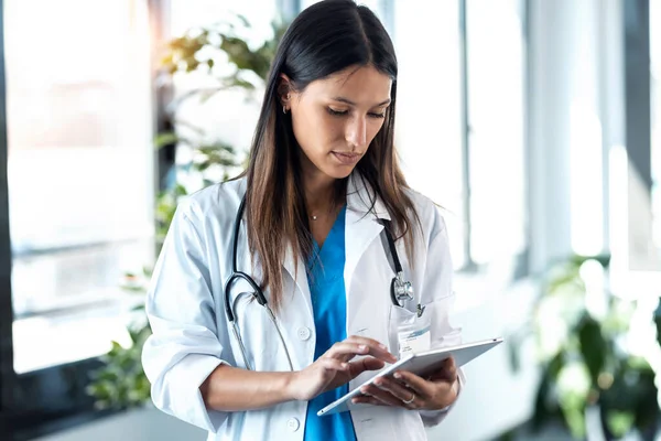 診察中に患者の病歴をデジタルタブレットで確認する自信に満ちた若い女性医師のショット — ストック写真