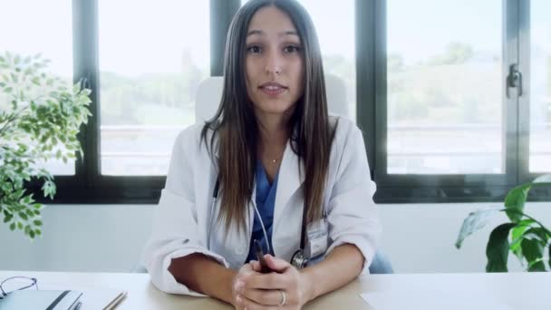 相談中のラップトップとのビデオ通話を通じて同僚と話す女性医師のビデオ — ストック動画