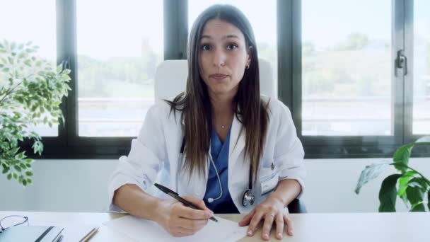 相談中のラップトップとのビデオ通話を通じて同僚と話す女性医師のビデオ — ストック動画