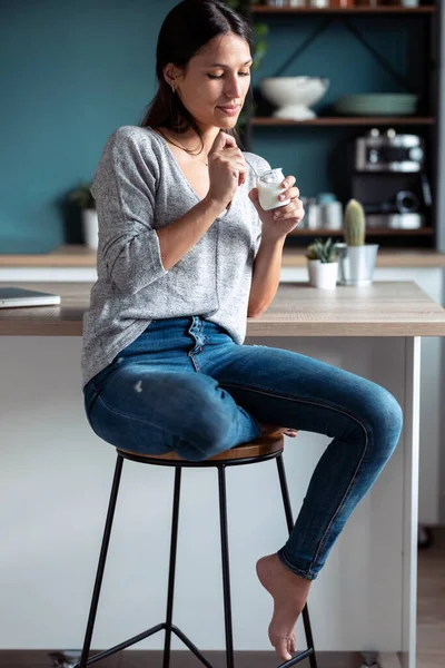 Evdeki Mutfaktaki Taburede Otururken Yoğurt Yiyen Gülümseyen Bir Genç Kadın — Stok fotoğraf