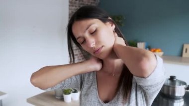 Evdeki mutfaktaki taburede otururken boynu ağrıyan genç bir kadının videosu..