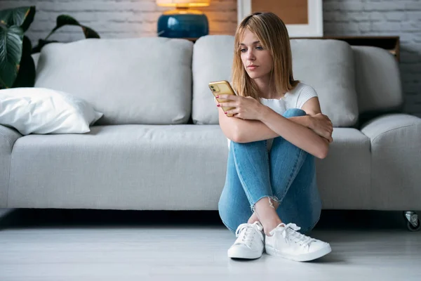 Tiro Jovem Mulher Séria Usando Seu Telefone Celular Enquanto Sentada — Fotografia de Stock