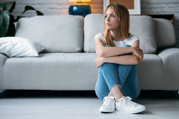 Foto Mujer Joven Reflexiva Mirando Hacia Lado Mientras Sienta Suelo — Foto de Stock