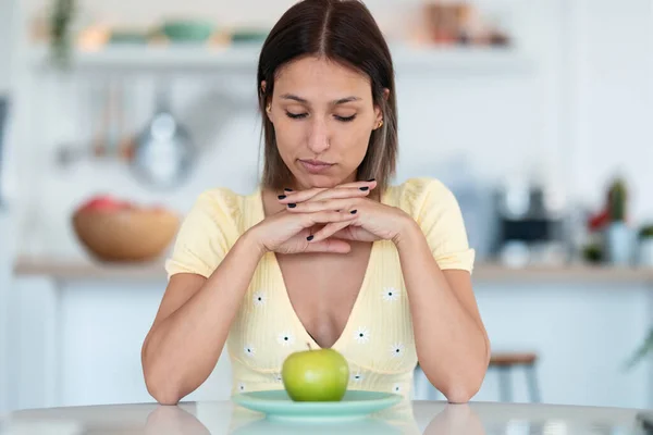自宅のキッチンに座っているプレート上に緑のリンゴを持つ美しい若い女性の肖像画 国会の概念 — ストック写真
