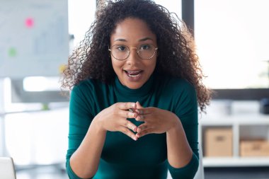 Ofisteki kameraya bakarak bir şey açıklayan güzel bir genç kadının portresi..