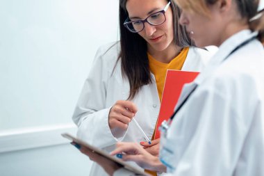 Hastanede dijital tablet tutarken birbiriyle konuşan iki güzel kadın doktor..