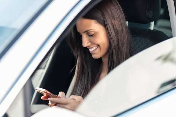 車の中で彼女の携帯電話でメッセージを送信する美しい若い女性の肖像画 — ストック写真