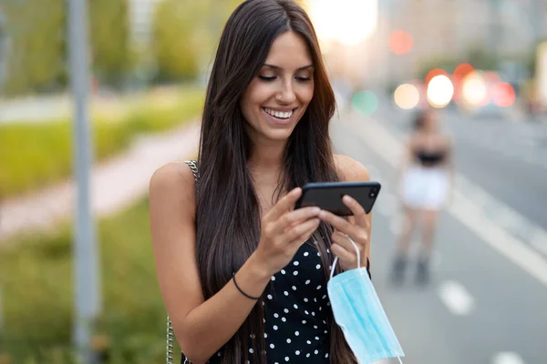 Colpo Giovane Donna Che Tiene Maschera Protettiva Durante Utilizzo Smartphone — Foto Stock