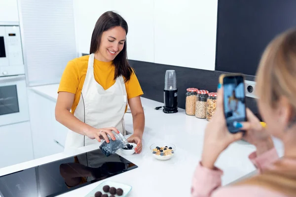 부엌에서 건강에 요리를 준비하는 동안젊은 여자가 자신의 영양사의 비디오를 녹화하고 — 스톡 사진