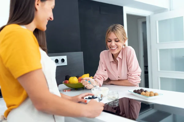 彼らは自宅でキッチンで準備している健康的な料理を味わう2人の美しい女性のショット — ストック写真