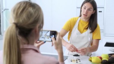 Genç bir kadının, genç ve profesyonel beslenme uzmanının evde sağlıklı yemekler hazırlarken videosunu kaydettiği video..