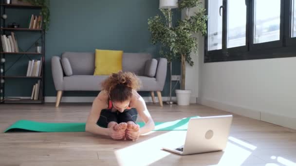 자신감 여성이 거실에서 노트북을 온라인 체육관 수업을 따라고 운동을 모습을 — 비디오
