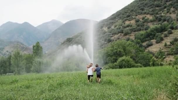 Video Una Hermana Hermano Pequeño Divirtiéndose Jugando Con Agua Aspersor — Vídeo de stock