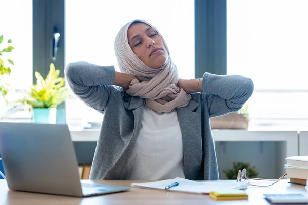 オフィスで首の痛みを持つヒジャーブを身に着けている疲れた若いイスラム教徒のビジネス女性のショット — ストック写真