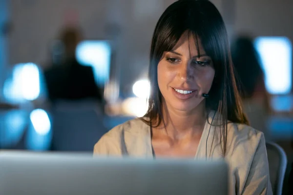 Zdjęcia Pięknej Uśmiechniętej Młodej Bizneswoman Pracującej Laptopem Podczas Rozmowy Słuchawką — Zdjęcie stockowe