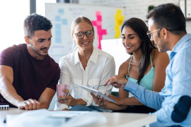 Ofiste dijital tablete bakarken yeni projeleri hakkında konuşan ve çalışan çok yönlü iş adamlarının fotoğrafları..