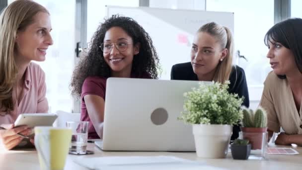 四个漂亮聪明的女商人一边在办公室的工作空间里聊天 一边在办公桌上用笔记本电脑和数字平板电脑工作的视频 — 图库视频影像