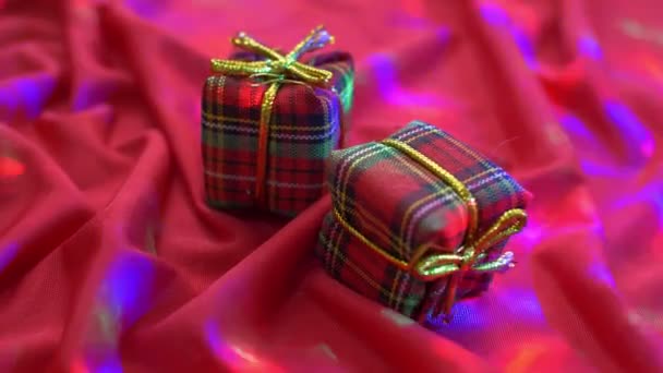 Rote Geschenkschachteln auf seidenem Hintergrund mit Lichtern — Stockvideo