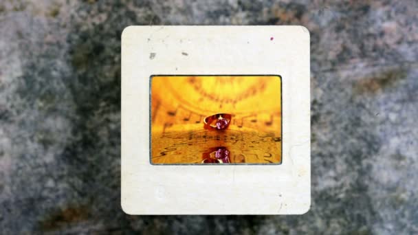 Bague dorée sur feuille de musique réfléchissant dans l'eau sur film de diapositive vintage — Video