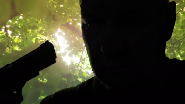 Силуэт серьезного мужчины с пистолетом в руках и готовящегося к самоубийству — стоковое видео