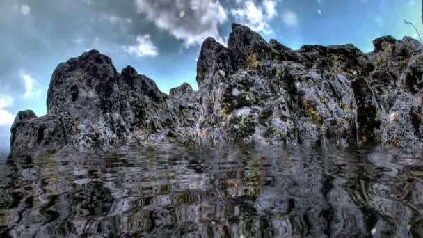 Nieva sobre una montaña rocosa reflejada en el agua — Vídeos de Stock