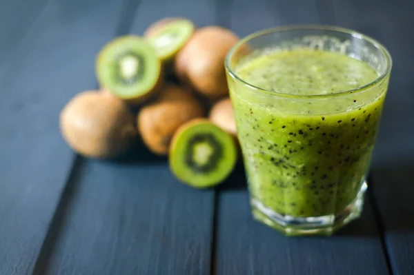 Vidro de suco de kiwi com frutas frescas na mesa de madeira preta Fotos De Bancos De Imagens