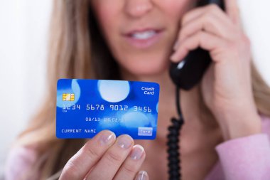Close-up Of Mature Woman Holding Credit Card While Talking On Telephone clipart