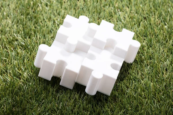Dört Beyaz Jigsaw Puzzle Yükseltilmiş Görünümünü Yeşil Çimenlerin Üzerinde — Stok fotoğraf