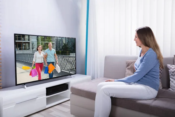 Frau Liegt Mit Taschenrechner Auf Sofa Während Sie Hause Fernsieht — Stockfoto