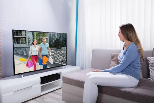 Mulher Deitada Sofá Usando Calculadora Enquanto Assiste Televisão Casa — Fotografia de Stock