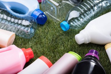 Yeşil çimenlerin üzerinde plastik su şişesi türleri