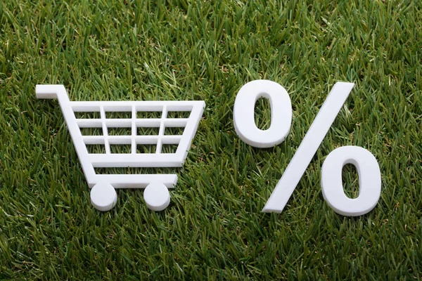 ショッピング カートと緑の芝生にパーセント記号白いミニチュアのハイアングル — ストック写真