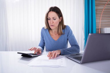 Ofiste beyaz masa hesap makinesiyle fatura hesaplama iş kadını Olgun