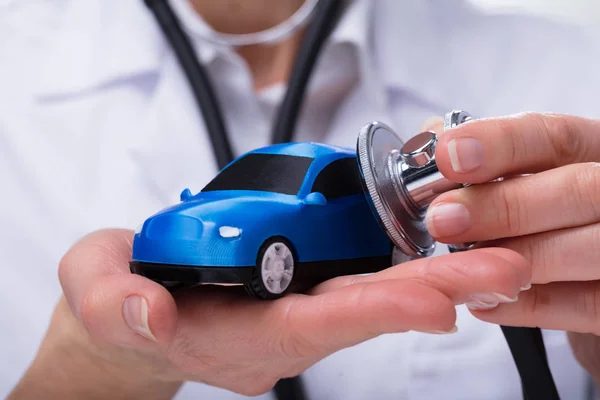 Doctor\'s Hand Examining Blue Car With Stethoscope