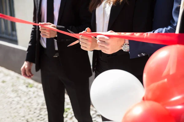 Close Van Ondernemers Hand Snijden Rood Lint Met Een Schaar — Stockfoto