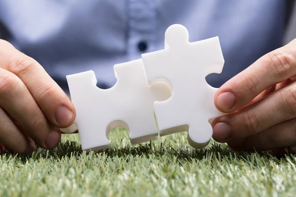Birinin Elini Iki Beyaz Jigsaw Puzzle Yeşil Çim Bağlanma — Stok fotoğraf