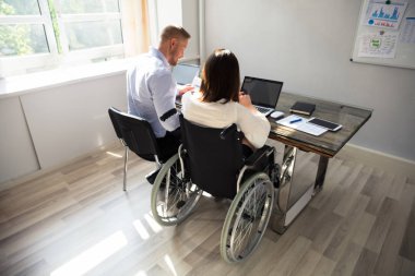 Dizüstü bilgisayar ile eşi ile Office Danışma üzerinde oturan Engelli iş kadını