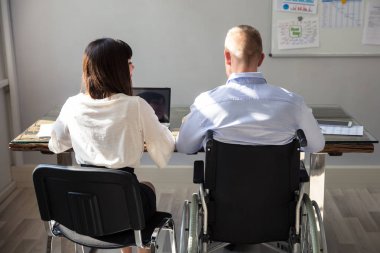 Arkadan Görünüş üstünde Laptop çalışma meslektaşı ile Engelli iş adamı