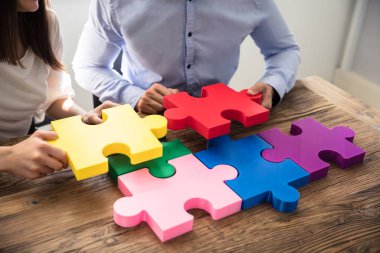 İki iş adamları üzerinde ahşap Resepsiyon çok renkli parçalı bulmaca çözme