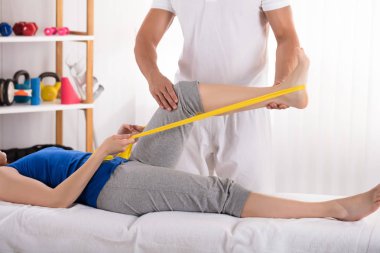 Kadın sarı Egzersiz Band ile bacak tedavi veren fizyoterapist