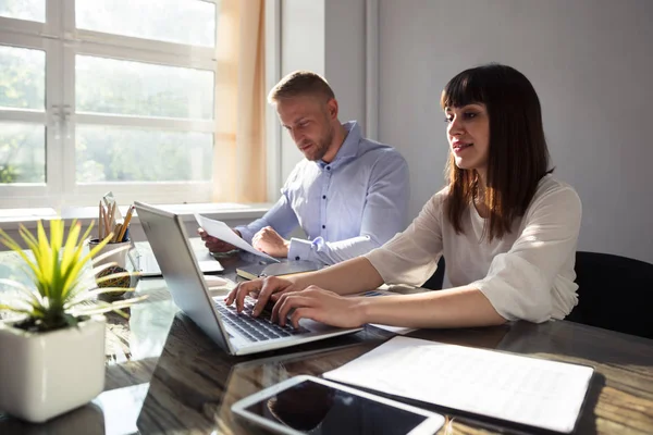 Ofiste dizüstü bilgisayar üzerinde çalışan iki genç iş adamları