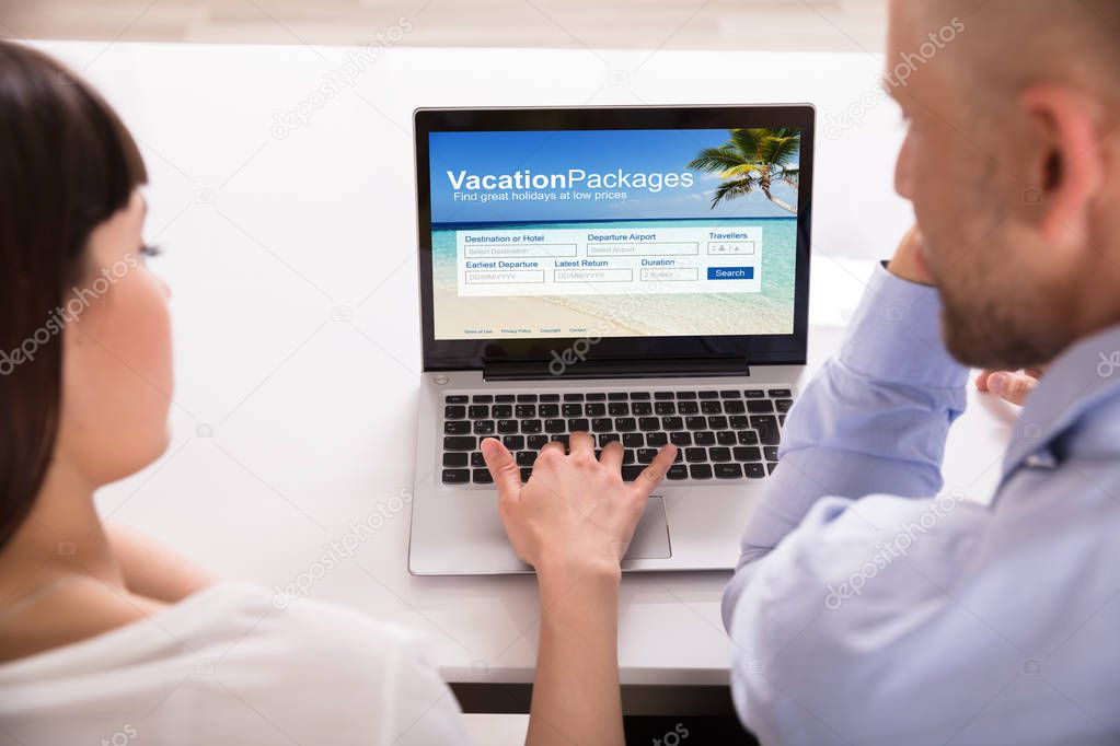 Close-up Of A Couple Filling Online Vacation Packages Form On Laptop