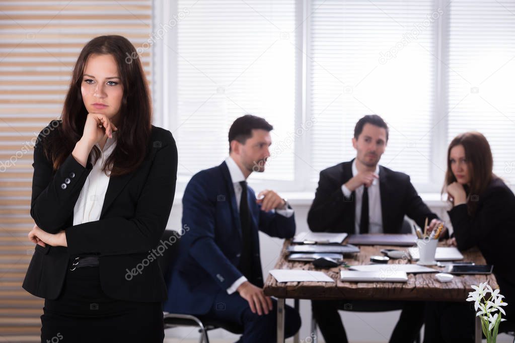 Portrait Of A Sad Businesswoman In Front Of Her Colleagues Sitting In Office