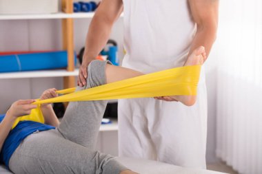 Kadın sarı Egzersiz Band ile bacak tedavi veren fizyoterapist