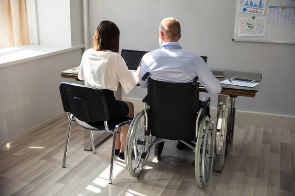 Arkadan Görünüş üstünde Laptop çalışma meslektaşı ile Engelli iş adamı