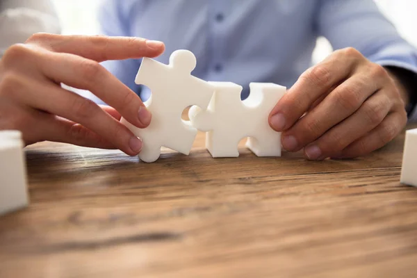 Close Two Businesspeople White Jigsaw Pieces Wooden Desk — Stock Photo, Image