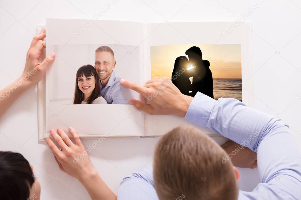 High Angle View Of A Couple Looking At Their Photo Album Over White Background