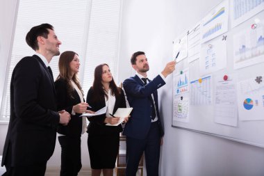 Grup Genç İşadamları Office beyaz tahta üzerinde bağlı grafikleri bakarak