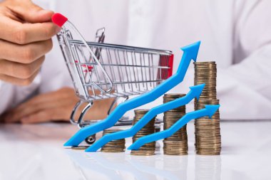 Alışveriş sepeti tutan insan el önünde artan yığılmış jetonlu ok mavi